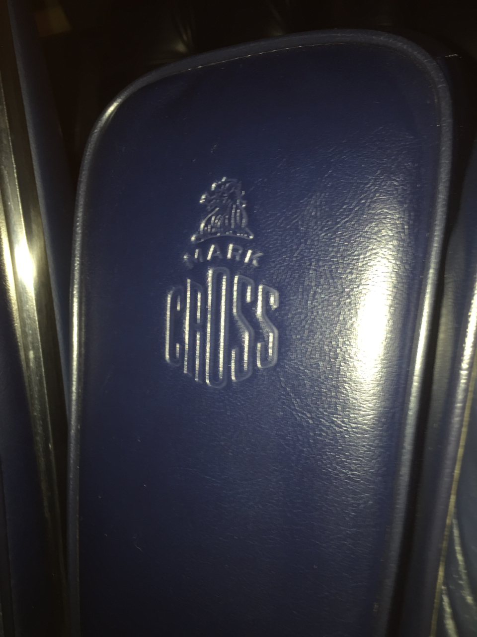 The front armrest, when in the up position, has the Mark Cross logo embossed in the leather.